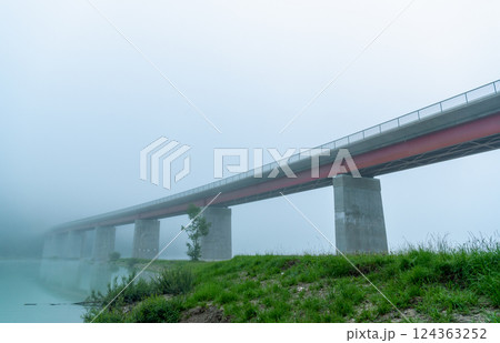 Bridge over Sylvenstein lake on a foggy morning, side view from under the bridge Bridge over Sylvenstein lake on a foggy morning, side view from under the bridge 124363252