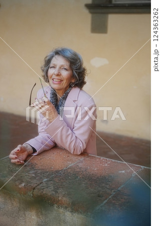 Elderly Woman Smiling Warmly While Holding Glasses Elderly Woman Smiling Warmly While Holding Glasses 124363262