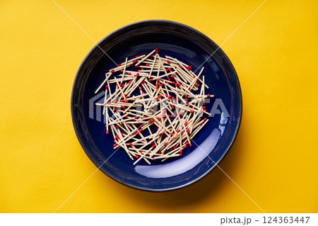 Matches in dark blue bowl over yellow background Matches in dark blue bowl over yellow background 124363447