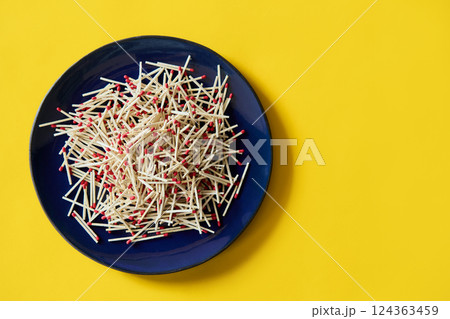 Matches in dark blue bowl over yellow background 124363459