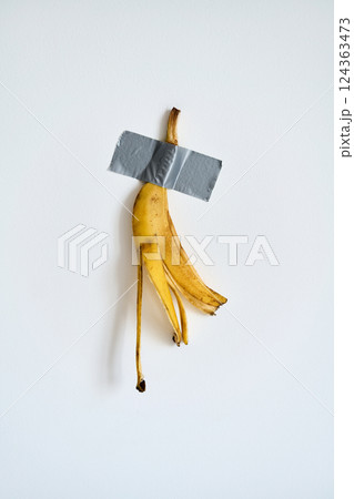 Banana peel taped to white wall 124363473
