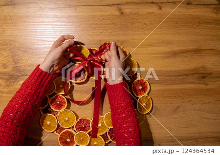 Step 3 DIY process of woman tying ribbon Christmas arrangement with dried oranges and grapefruits. Series of handmade craft instruction. Zero waste eco-friendly winter holiday decoration Step 3 DIY process of woman tying ribbon Christmas arrangement with dried oranges and grapefruits. Series of handmade craft instruction. Zero waste eco-friendly winter holiday decoration 124364534