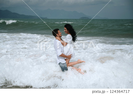 Happy young beautiful couple in love hugging in water on the beach by the sea in summer on vacation 124364717