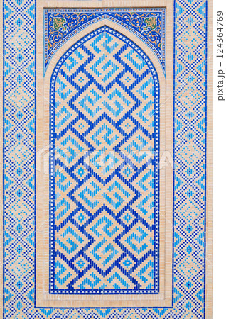 wall of Muslim mosque decorated with ceramic tiles with a traditional oriental Uzbek Islamic pattern 124364769