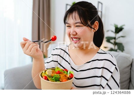 An Asian fat woman feels bad and bored while eating a salad. She doesn't like to eat vegetables 124364886