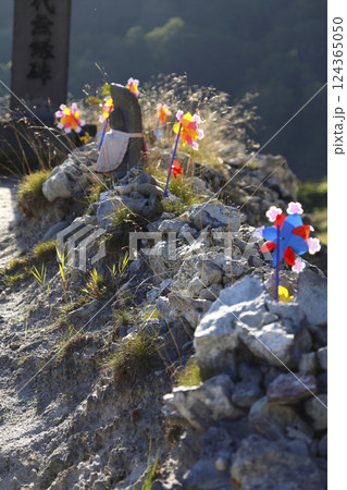 恐山の荒涼とした岩肌のお地蔵さまと石積み、風車 124365050