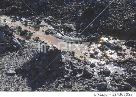 恐山の荒涼とした岩肌と石積み、間を流れる温泉水 恐山の荒涼とした岩肌と石積み、間を流れる温泉水 124365058