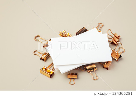 Blank business card on gold binder clips on light beige background Blank business card on gold binder clips on light beige background 124366281