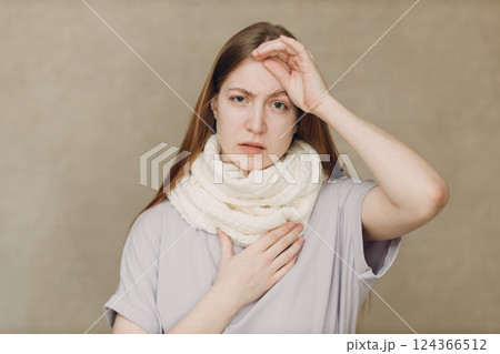 Young woman wearing scarf holds head flu catarrh ill sick disease treatment cold Young woman wearing scarf holds head flu catarrh ill sick disease treatment cold 124366512
