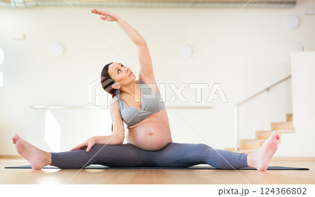 Pregnant woman is engaged in yoga. Revolved seated side angle pose or Parivrtta Upavistha Konasana 124366802