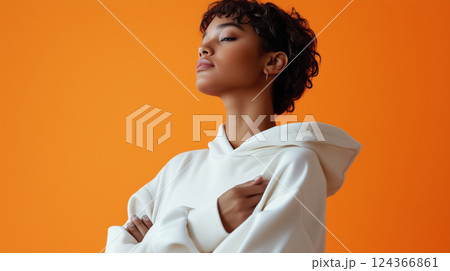 Portrait of a beautiful afro girl in a white hoodie on an orange background 124366861