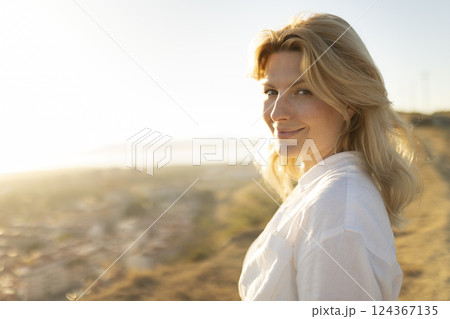 Blond woman enjoying golden hour light in scenic overlook Blond woman enjoying golden hour light in scenic overlook 124367135