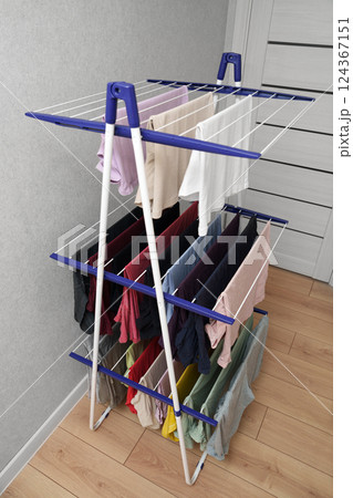 Clean clothes on the white three-tiered dryer in the apartment. Clean clothes on the white three-tiered dryer in the apartment. 124367151