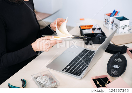 Jewelry business owner planning and managing inventory in a creative workspace. Small business, handmade jewelry, entrepreneurship, branding, digital strategy, e-commerce 124367346