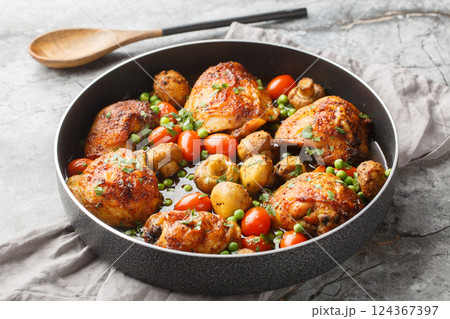 Fried chicken thighs with mushrooms, green peas, cherry tomatoes and herbs close-up in a frying pan. Horizontal Fried chicken thighs with mushrooms, green peas, cherry tomatoes and herbs close-up in a frying pan. Horizontal 124367397