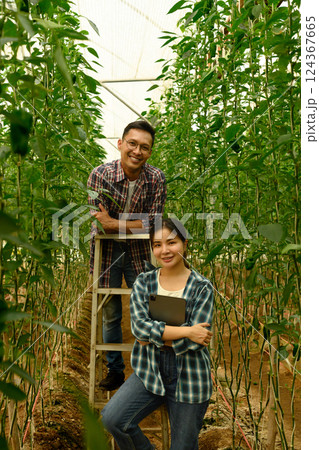 Male and female farmers pose among growing bell peppers Male and female farmers pose among growing bell peppers 124367665