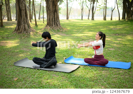 Man and woman stretching exercise on yoga mats in a serene outdoor park 124367679