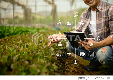 Farmer analyzing crop data on digital tablet in the greenhouse. IoT in farming and smart agriculture concept Farmer analyzing crop data on digital tablet in the greenhouse. IoT in farming and smart agriculture concept 124367856