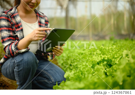 Cropped shot female farmer using digital tablet in organic farm Cropped shot female farmer using digital tablet in organic farm 124367861