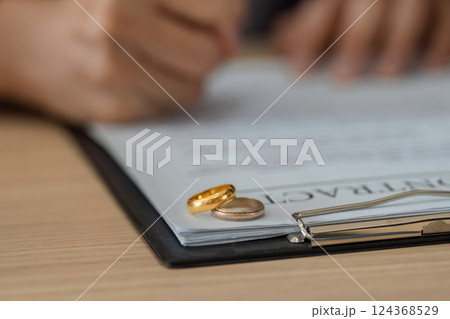 Divorce Proceedings and Acknowledgment. Wedding rings placed on top of legal documents signify a separation. Divorce Proceedings and Acknowledgment. Wedding rings placed on top of legal documents signify a separation. 124368529