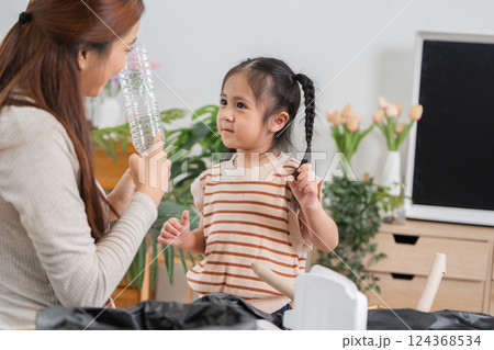 Recycling and Teaching. A mother and daughter engaged in a fun recycling session at home. Recycling and Teaching. A mother and daughter engaged in a fun recycling session at home. 124368534
