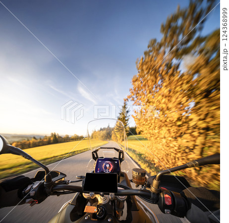 Detail of motorcycle handlebars. View from driver perspective, beautiful rural landscape in sunset light. Detail of motorcycle handlebars. View from driver perspective, beautiful rural landscape in sunset light. 124368999