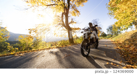 Motorcyclist rides through scenic autumn forest trail. Motorcyclist rides through scenic autumn forest trail. 124369000