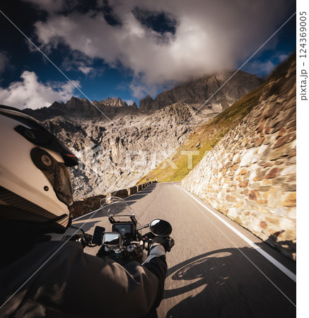 Detail of motorcycle handlebars. View from driver perspective, beautiful Alpine landscape in sunset light. Detail of motorcycle handlebars. View from driver perspective, beautiful Alpine landscape in sunset light. 124369005