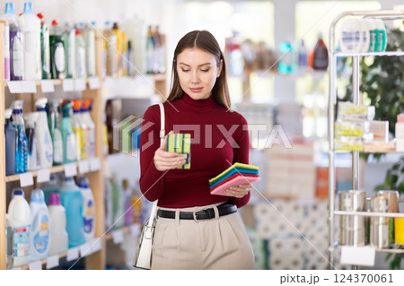 Young woman chooses sponges and rags in store 124370061