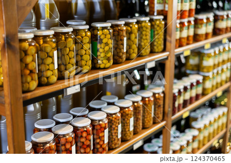 Marinated whole unpitted green olives in jars on shelf rack in store Marinated whole unpitted green olives in jars on shelf rack in store 124370465