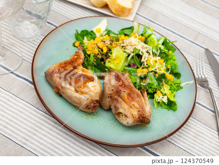 Fried quail garnished with portion of fresh vegetable salad 124370549