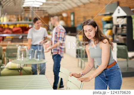 Girl buyer choose chair in garden furniture store showroom Girl buyer choose chair in garden furniture store showroom 124370620
