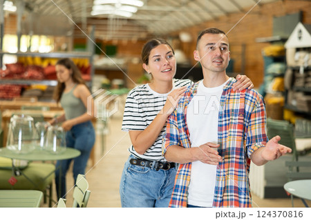 Spouses look for something in furniture store, searching for perfect item to complete patio Spouses look for something in furniture store, searching for perfect item to complete patio 124370816