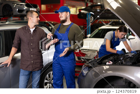 Young male mechanic giving car keys to guy client Young male mechanic giving car keys to guy client 124370819