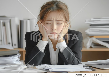 仕事が多すぎてやる気がないスーツ姿の若い女性。背景はオフィス 仕事が多すぎてやる気がないスーツ姿の若い女性。背景はオフィス 124371192