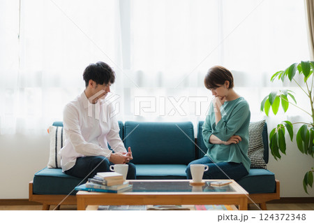 真剣に話し合う若いカップル – 自宅リビングでの考え込む表情 124372348