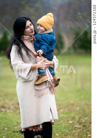 Woman holds her child in a rural setting looking lovingly at him on an overcast day enjoying their togetherness and expressing her affection Woman holds her child in a rural setting looking lovingly at him on an overcast day enjoying their togetherness and expressing her affection 124372388