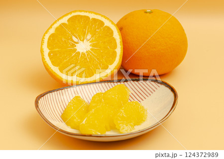紅夏みかんの断面とむいた果肉が小皿に乗っている素材写真 124372989