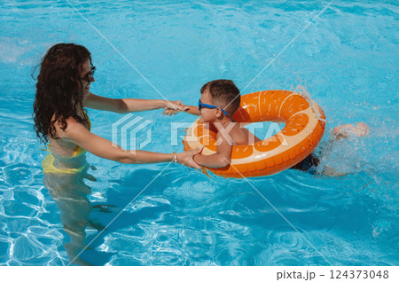 young mother teaches her child boy son to swim in swimming pool at a hotel on vacation at resort in the summer young mother teaches her child boy son to swim in swimming pool at a hotel on vacation at resort in the summer 124373048
