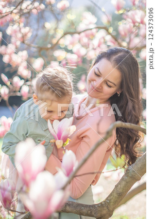 Trendy mom with her little daughter under blooming magnolia trees in a Prague park. Capturing a stylish family moment with a modern approach to parenting Trendy mom with her little daughter under blooming magnolia trees in a Prague park. Capturing a stylish family moment with a modern approach to parenting 124373096