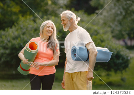 Senior man and woman with yoga mats standing at park. Positive mature man and his elderly wife after fitness or yoga class in nature. Wellness and healthy lifestyle on retirement. Senior man and woman with yoga mats standing at park. Positive mature man and his elderly wife after fitness or yoga class in nature. Wellness and healthy lifestyle on retirement. 124373528