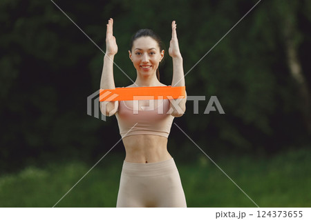 Pretty lady training on a summer beach. Brunette doing yoga. Girl in a sportsuit. 124373655