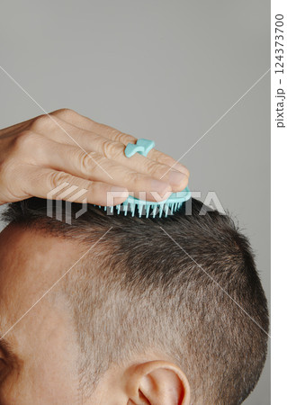 man combs his hair with a round scalp brush 124373700