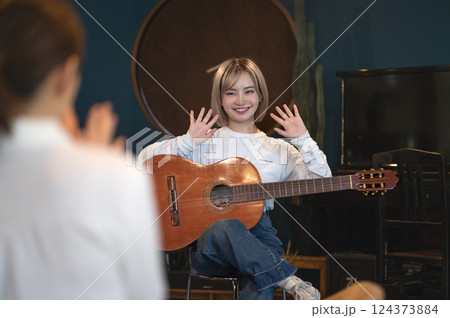 スタジオでアコースティックギターで弾き語りする若い女性 124373884