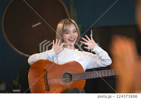 スタジオでアコースティックギターで弾き語りする若い女性 124373886