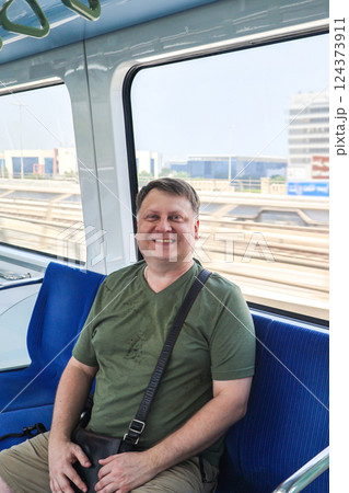 Man smiles toothily while sitting in a subway car Man smiles toothily while sitting in a subway car 124373911