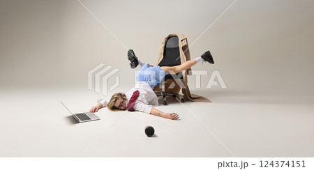 Office worker balancing upside down on chair, while working on laptop, reflecting instability of work-life balance. 124374151