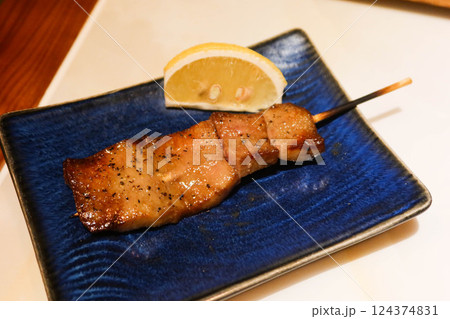 close up of grilled Japanese wagyu beef ox tongue skewer yakitori on a blue plate with lemon slice on the side in a izakaya restaurant  124374831
