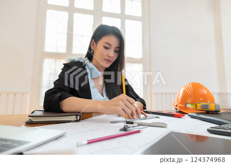 Female architect working on blueprint architects project in office. Female architect working on blueprint architects project in office. 124374968
