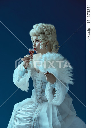 Cheers. Rococo-styled woman raising glass of liquor, framed by white fan. Cheers. Rococo-styled woman raising glass of liquor, framed by white fan. 124375254